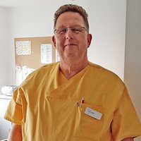 Arbeitszeitkampagne_Holger Portraitfoto von einem OP-Pfleger in Arbeitskleidung